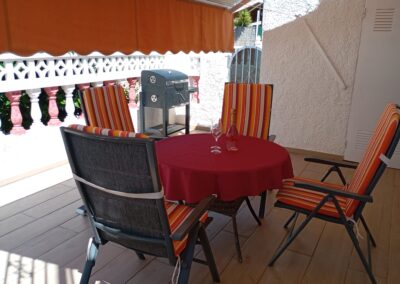 Terrasse couverte de Casa La Pequeña avec table, fauteuils et barbecue à Torrevieja